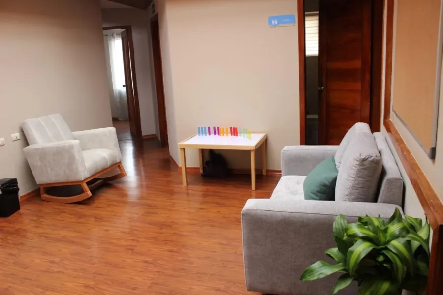 Sala de espera acogedora de Anesis, con mecedora y sofá